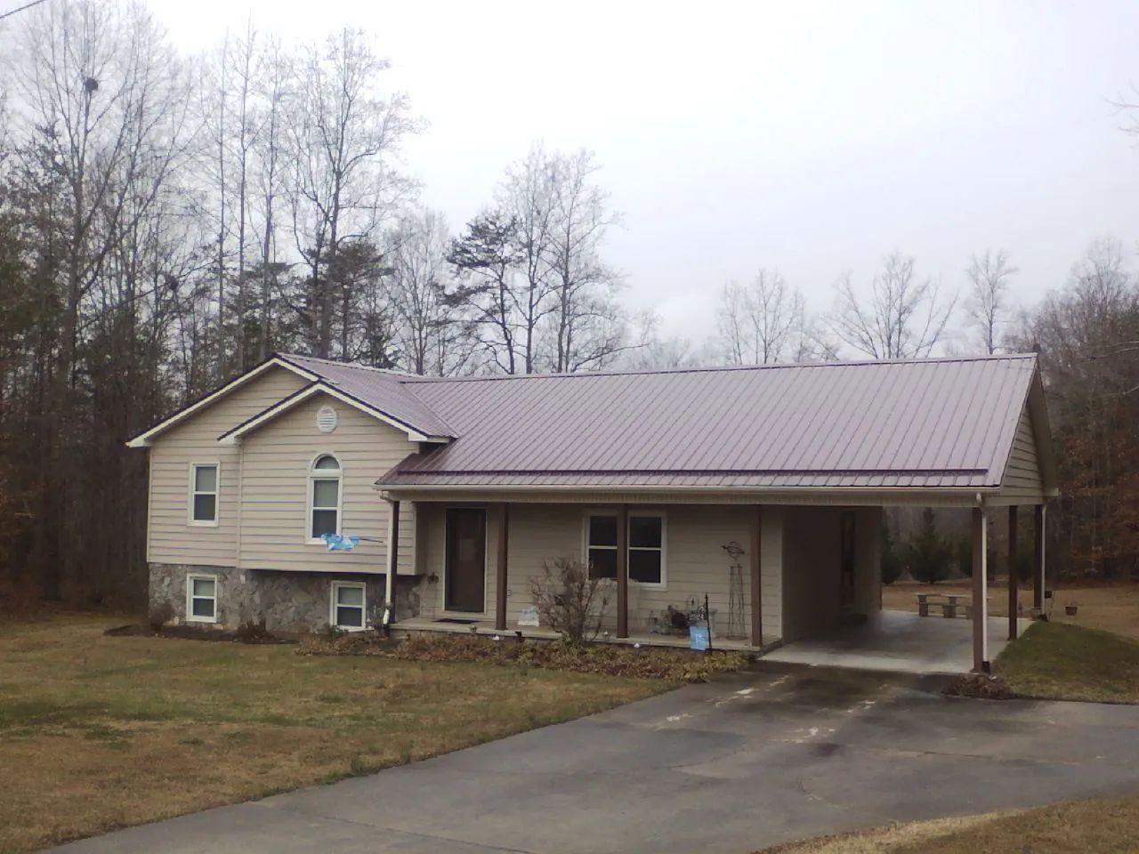Burgundy metal roof on a tan split level home with an attached carport in Prince Frederick