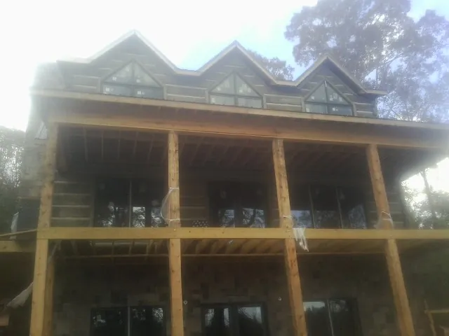 Dormers and porch framing on a large log home under construction — Roof Coating work by our crew in Prince Frederick