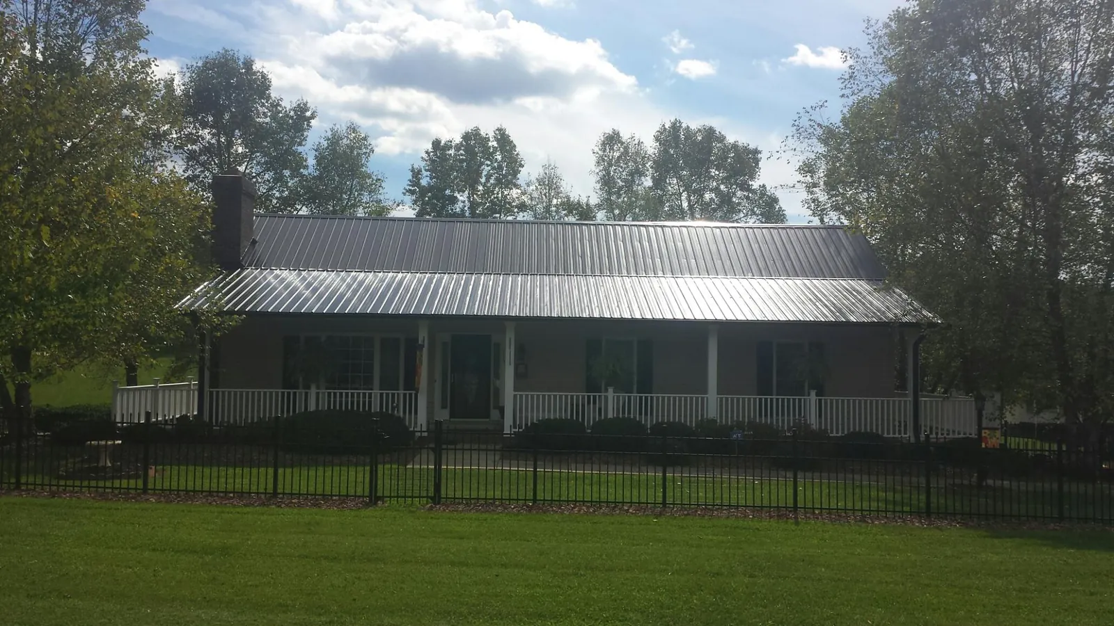 Gray metal roof on a brick ranch with a full width front porch — Gutter Guard Installation work by our crew in Prince Frederick
