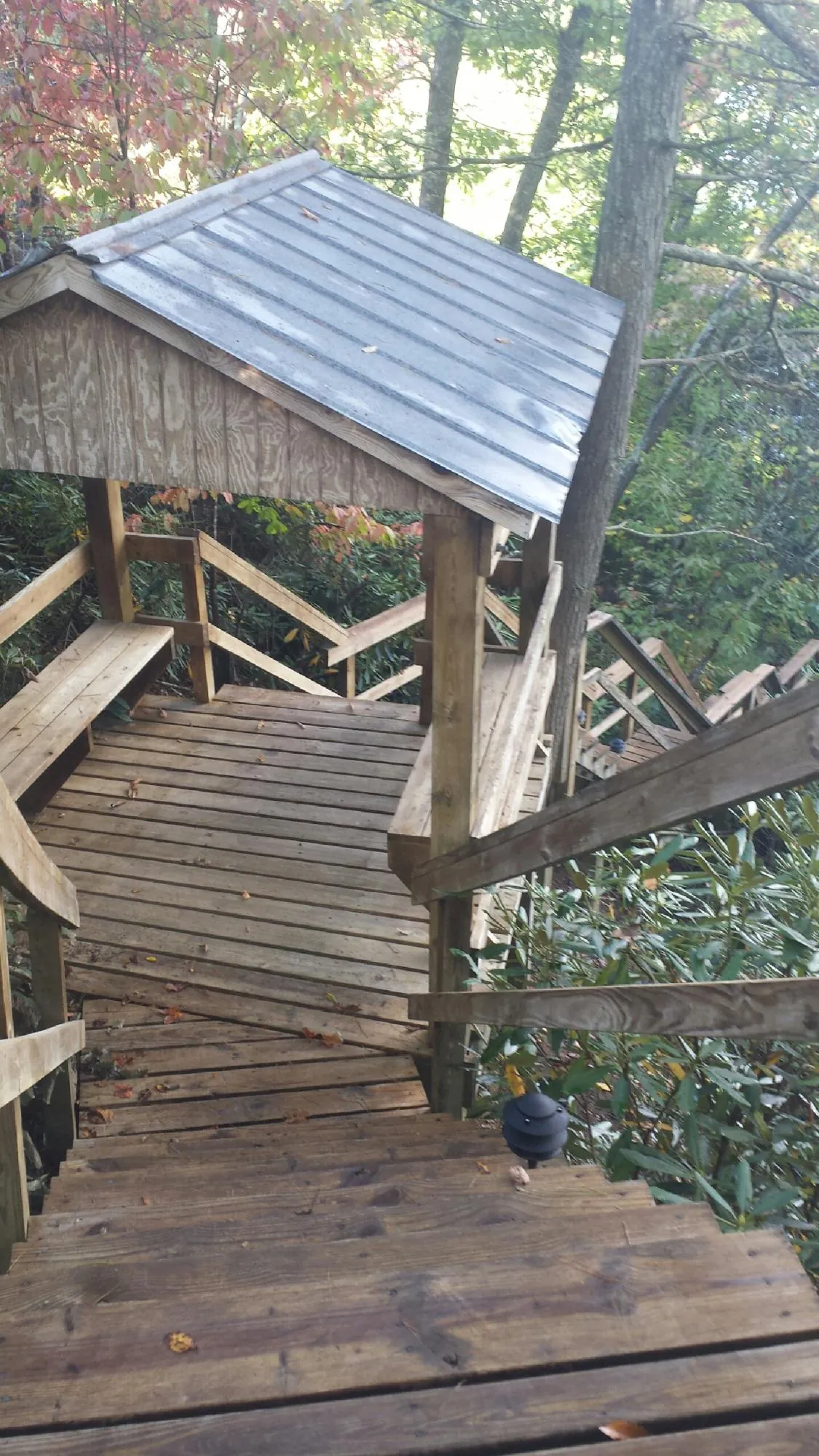Metal roofed shelter over wooden steps on a wooded walkway — Skylight Repair & Installation work by our crew in Prince Frederick