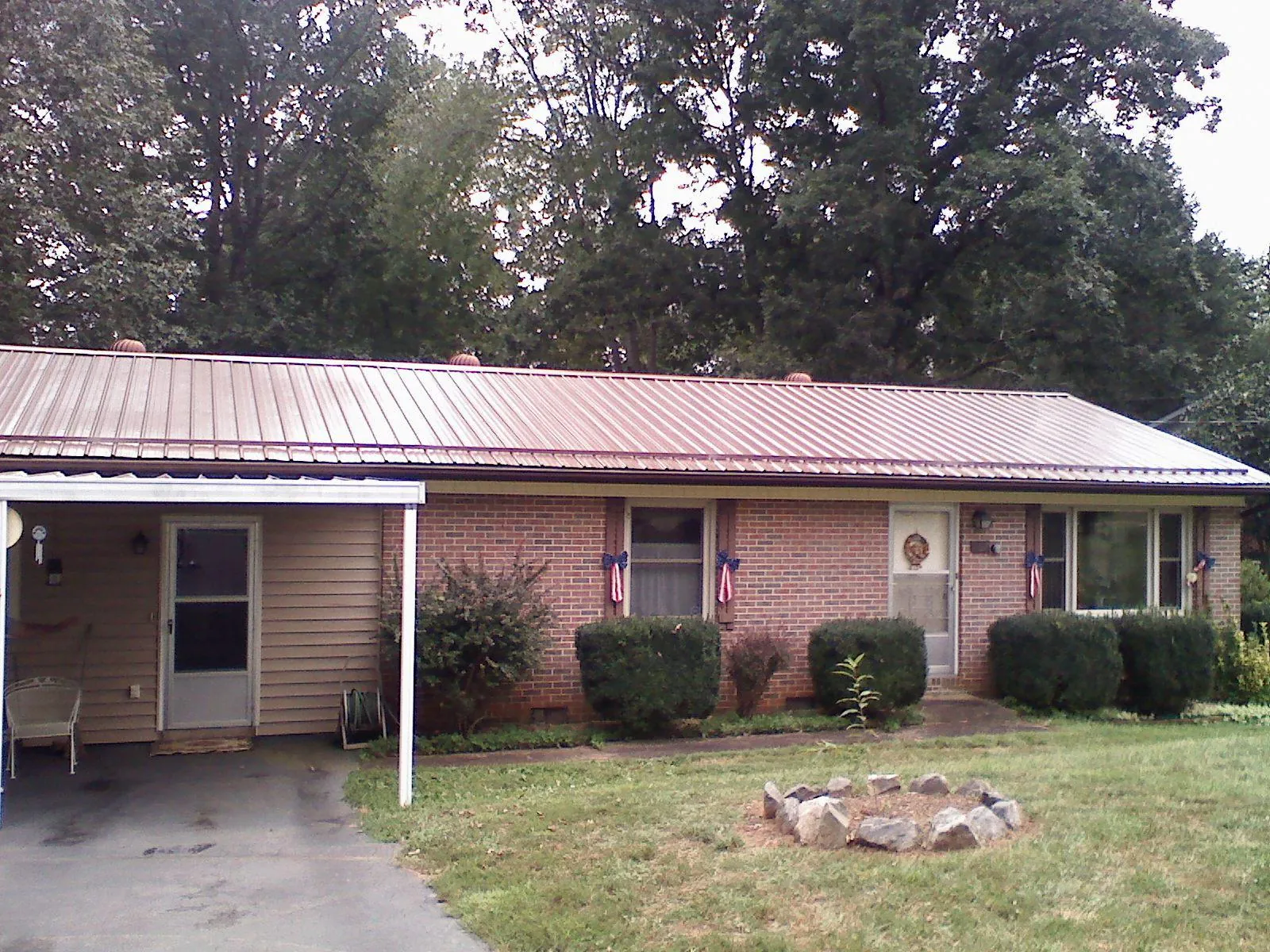 Bronze metal roof and carport on a brick ranch home — Roof Repair work by our crew in Prince Frederick